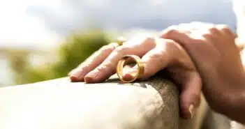 person holding gold wedding band